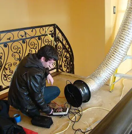 Training my grandson to to operate a duct blaster to test for HVAC duct leakage on a job site.