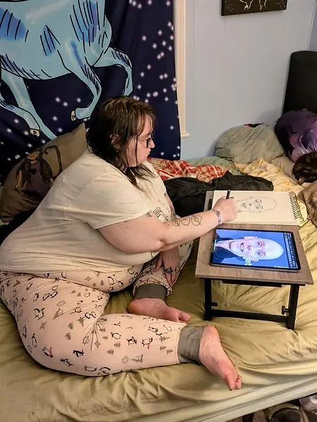 A picture of myself sketching a portrait of Doug Jones on a lap desk