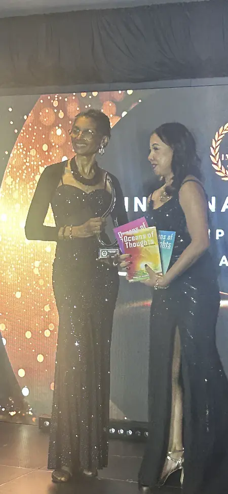 Rosalind Severin McClean receiving a winners trophy award for her Oceans of Thoughts Book Series at the 2025 International Impact Book Awards Grand Gala held in Phoenix, Arizona. The trophy was presented by Nim Stant, February 2025.