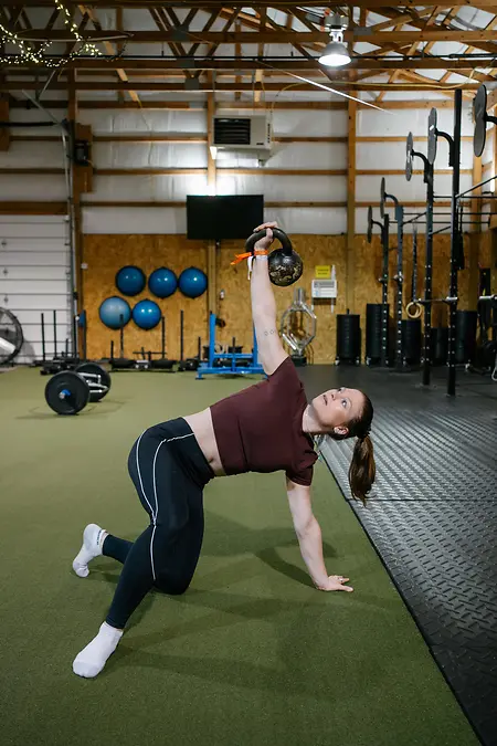 Caitlin demonstrates a Turkish Get-Up, a full-body kettlebell exercise that concentrates on core and shoulder stabilization, maintaining alignment, and a series of steps to go from the floor all the way up to a standing position while keeping a kettlebell up overhead and under control. 