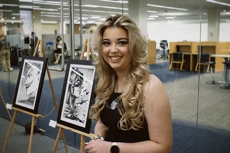 Bryna smiling with her selected artworks for the Penn State Harrisburg Artist Alliance’s 2026 Spring Art Show. 